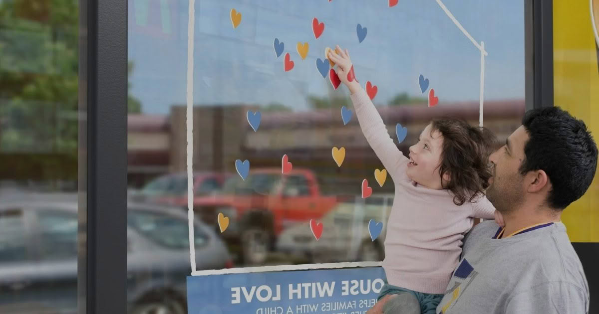 Dad holding daughter. Daughter points at McDonald's signage.